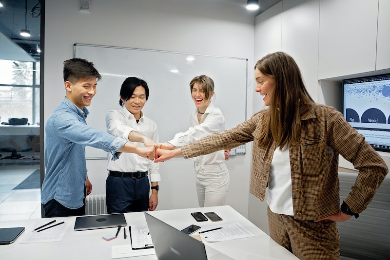 grupo de colaboradores dão as mãos durante reunião em escritório