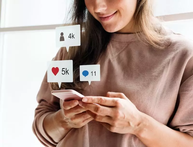 uma mulher consome conteúdos nas redes sociais, com ícones do engajamento das redes