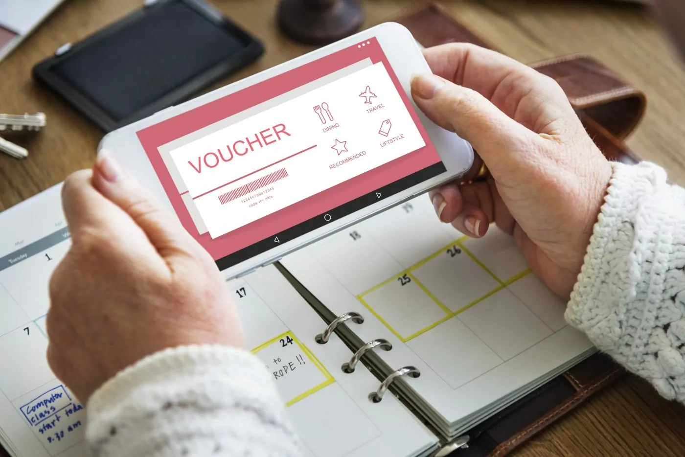 Uma senhora segura uma tela aberta em uma ada de vouchers, um dos benefícios do clube de vantagens